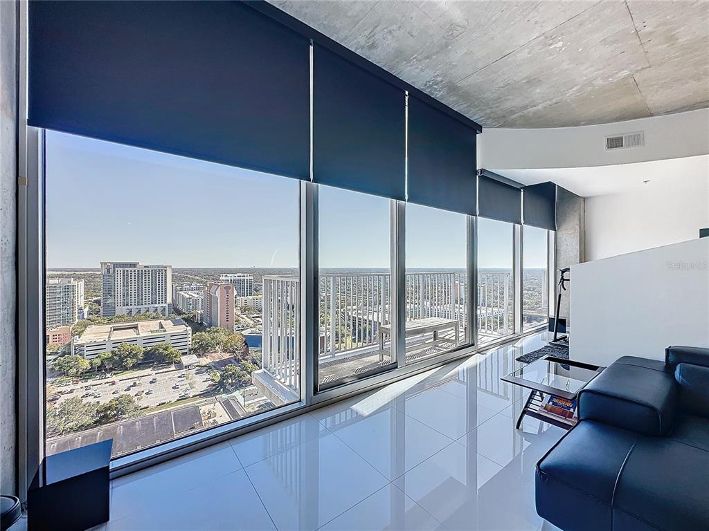 A modern living room with floor-to-ceiling windows, a balcony, and polished tile flooring — 155 S COURT AVENUE UNIT 2111, ORLANDO, FL