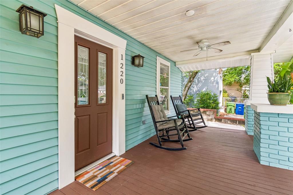 A teal bungalow with a front porch, palm trees, and a concrete retaining wall — 1220 E EMMA STREET, TAMPA, FL