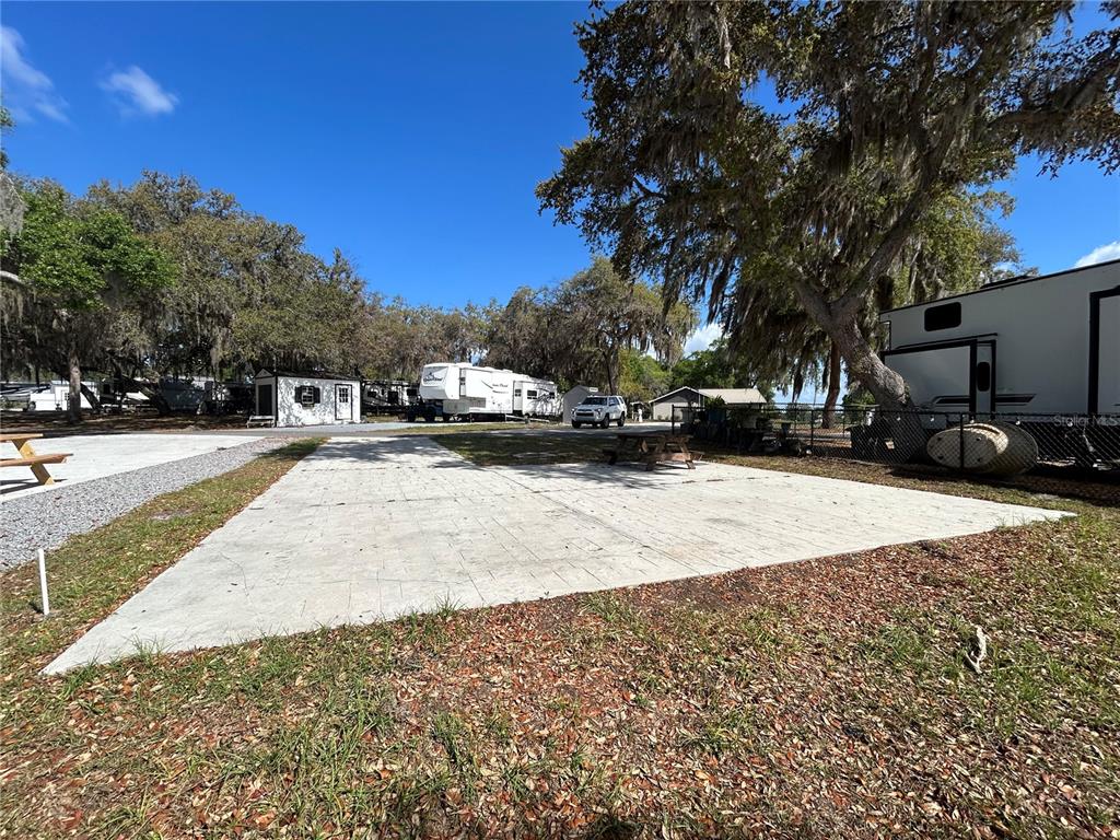 A wooden playground set with a climbing wall, slides, and swings sits on a grassy lawn — 15991 NE 243RD PLACE ROAD UNIT 54, FORT MC COY, FL