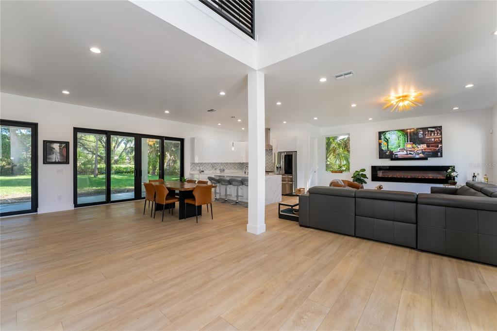 An open-concept living and dining area features light wood flooring, a fireplace, and sliding doors — 11113 LAKE BUTLER BOULEVARD, WINDERMERE, FL