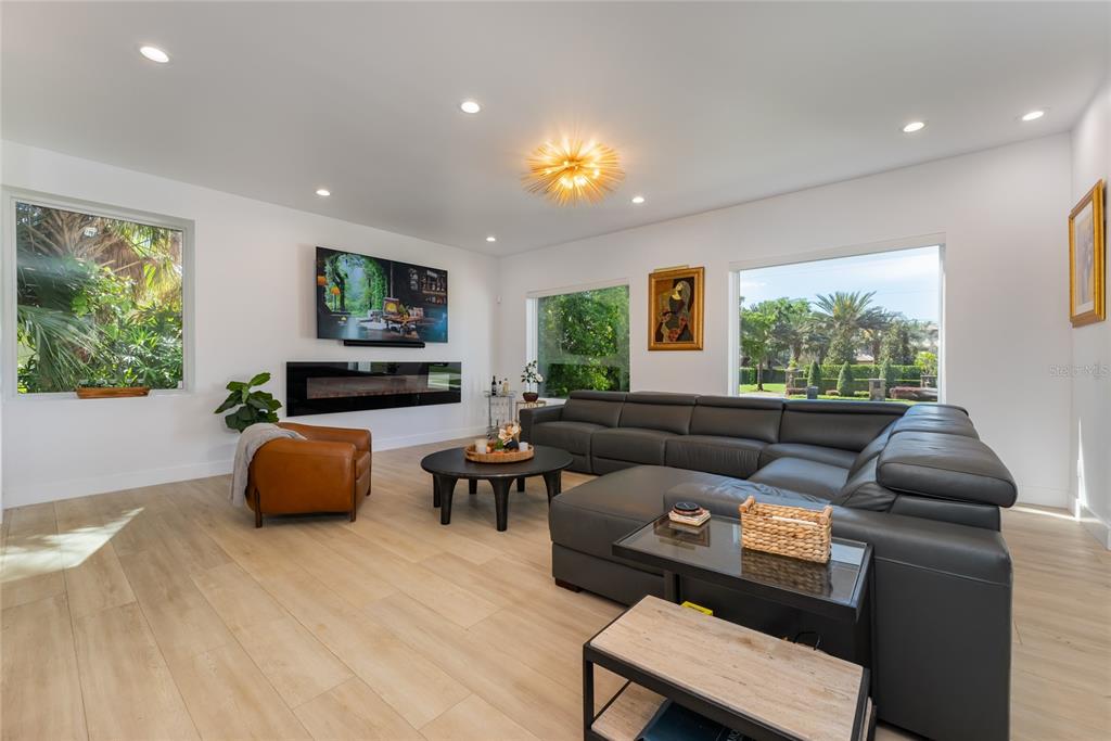 A living room features a dark leather sectional, a fireplace, and large windows with outdoor views — 11113 LAKE BUTLER BOULEVARD, WINDERMERE, FL