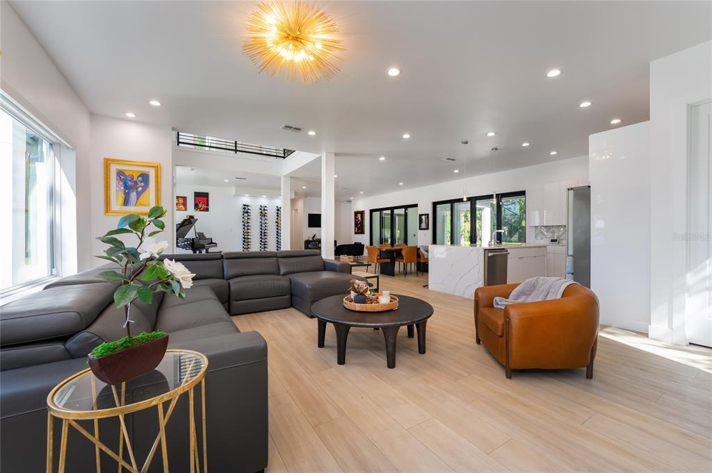 An open-concept living room features a gray sectional, leather armchair, and a modern kitchen — 11113 LAKE BUTLER BOULEVARD, WINDERMERE, FL