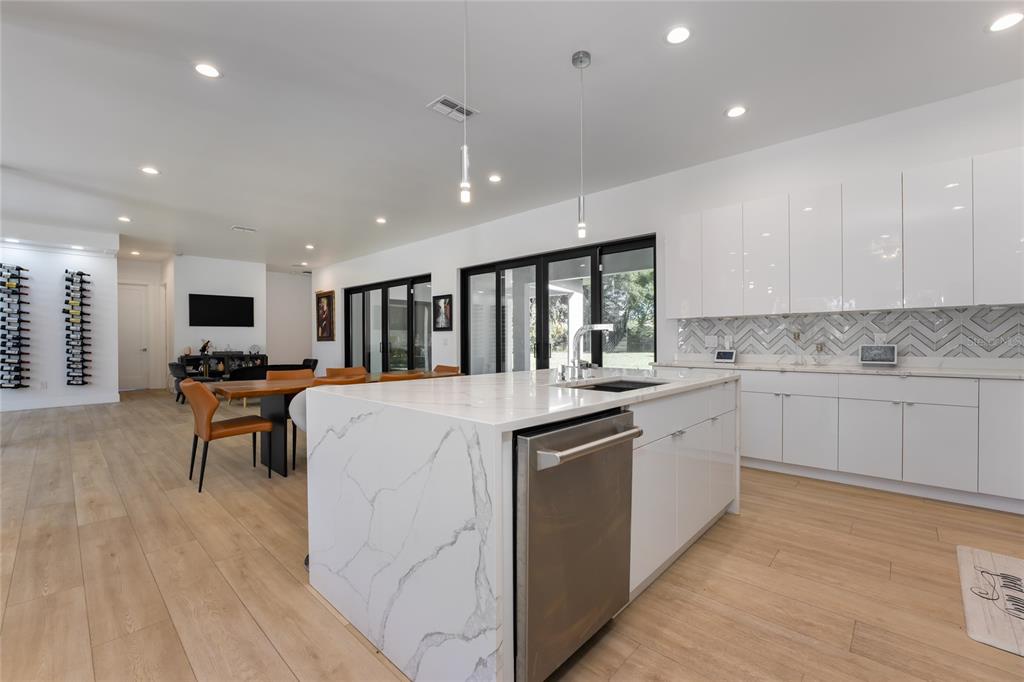 A modern kitchen features a marble-topped island, white cabinetry, and light wood flooring — 11113 LAKE BUTLER BOULEVARD, WINDERMERE, FL