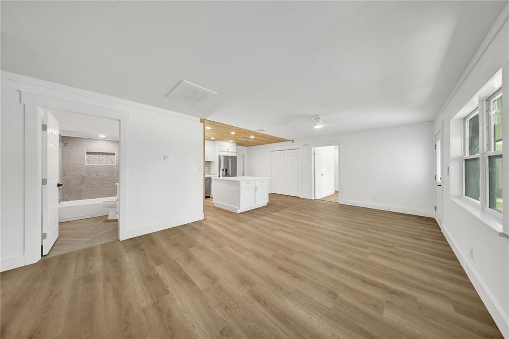 An open-concept living area features light wood flooring, white walls, and a kitchen with an island — 2264 WINCHESTER DRIVE, DUNEDIN, FL
