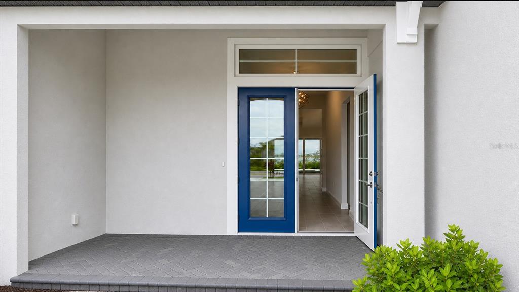 An aerial view shows a single-story house with a gray tile roof beside a lake — 812 BLUE SHELL LOOP, SARASOTA, FL