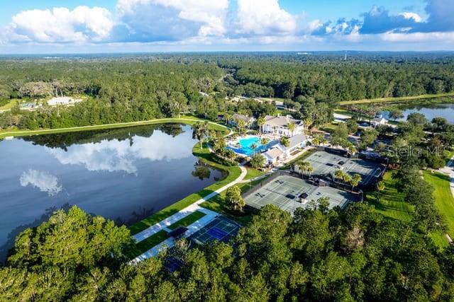 Aerial view of a lake, tennis courts, and a clubhouse surrounded by dense forest — 4563 SOUTHERN VALLEY LOOP, BROOKSVILLE, FL
