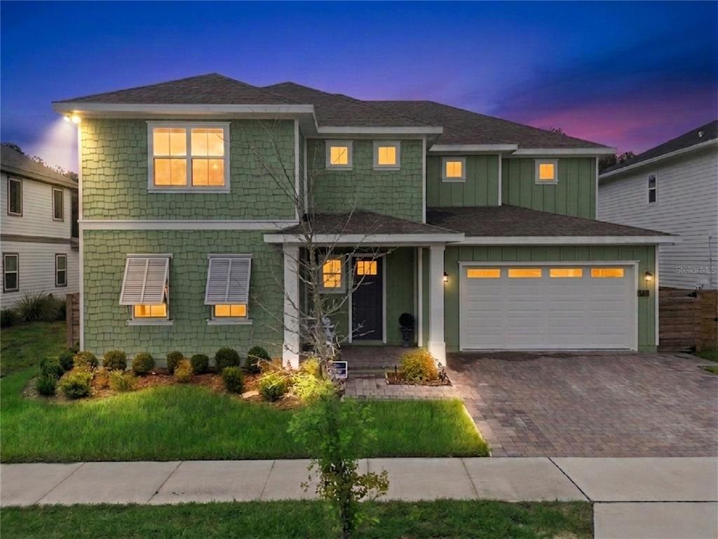 A two-story green house with a shingled exterior, a two-car garage, and a paved driveway — 6236 TRAILBLAZE BEND, ST CLOUD, FL