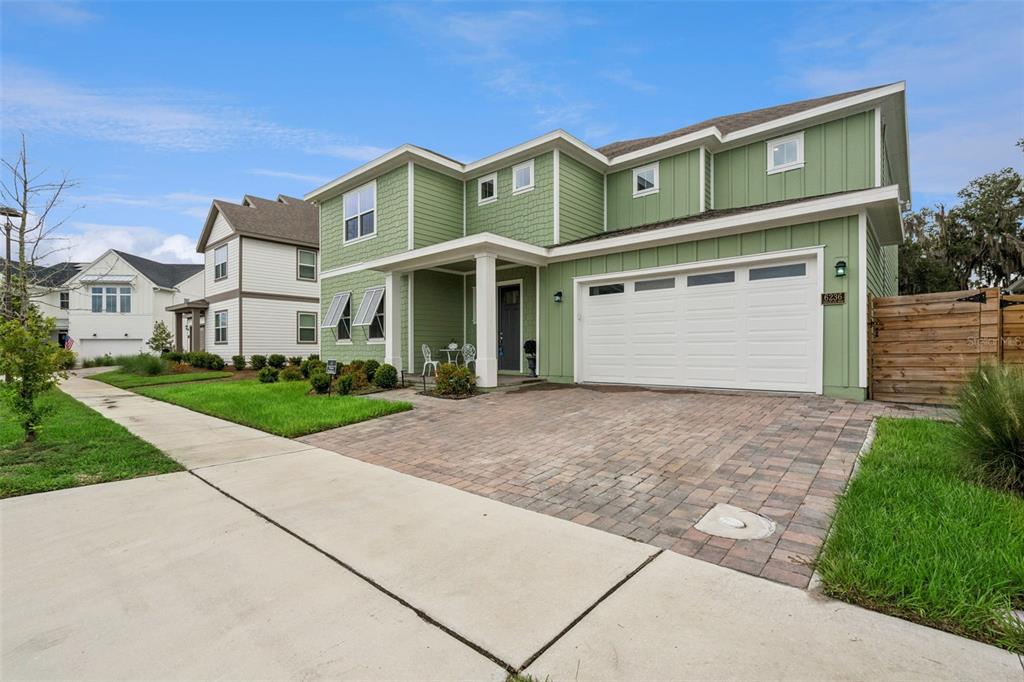 A two-story green house with a white garage and a brick paver driveway — 6236 TRAILBLAZE BEND, ST CLOUD, FL