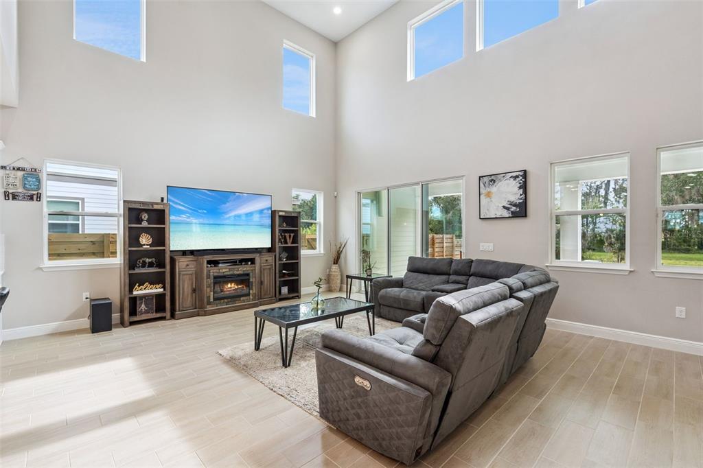 A spacious living room features high ceilings, light tile flooring, and a large sectional sofa — 6236 TRAILBLAZE BEND, ST CLOUD, FL