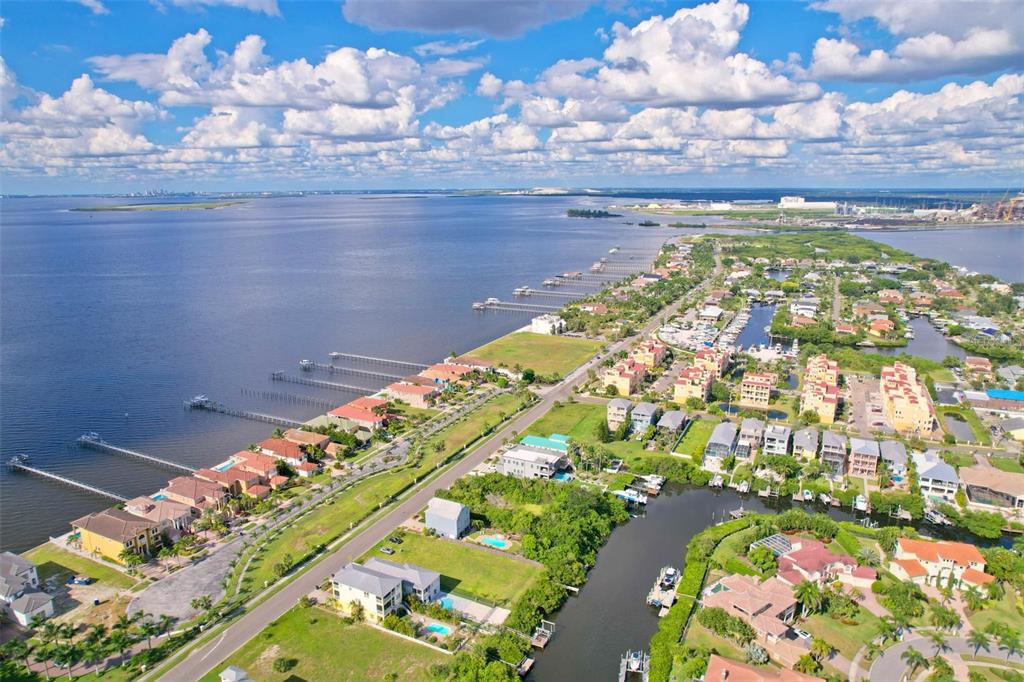 An aerial view shows a coastal neighborhood with houses, docks, and a canal — 6407 MARBELLA BOULEVARD, APOLLO BEACH, FL