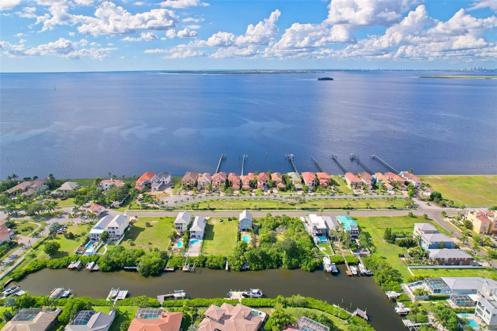 An aerial view shows waterfront houses along a canal and a large bay with docks — 6407 MARBELLA BOULEVARD, APOLLO BEACH, FL