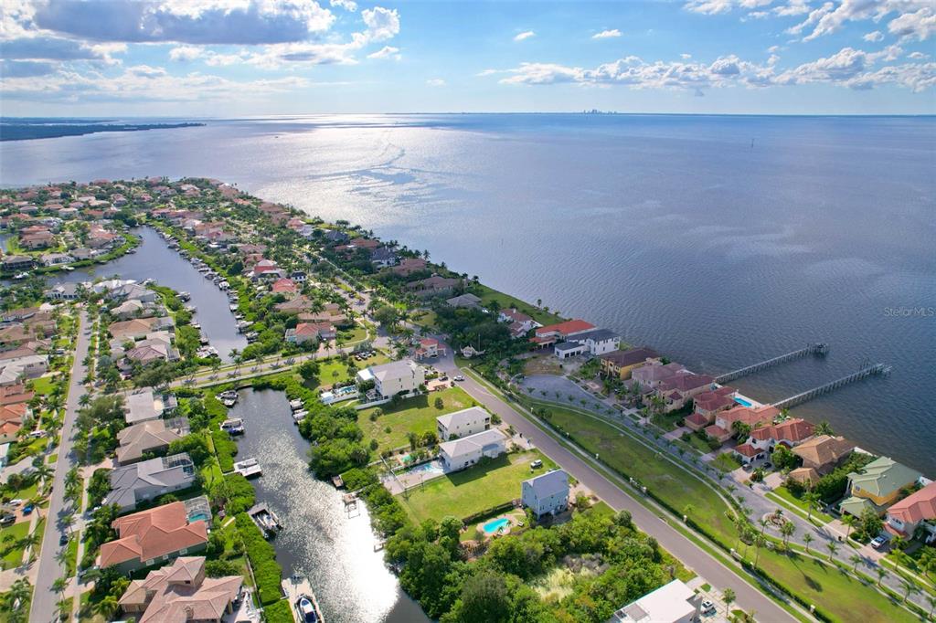 An aerial view shows a coastal neighborhood with houses, a canal, and a long pier — 6407 MARBELLA BOULEVARD, APOLLO BEACH, FL