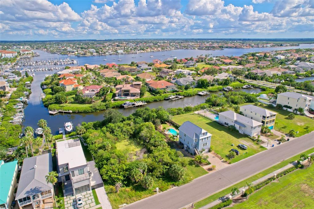 An aerial view shows waterfront houses, a canal with docked boats, and a residential street — 6407 MARBELLA BOULEVARD, APOLLO BEACH, FL