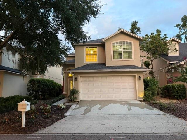 A two-story suburban house with a beige exterior, a two-car garage, and a concrete driveway — 1931 LOST SPRING COURT, LONGWOOD, FL