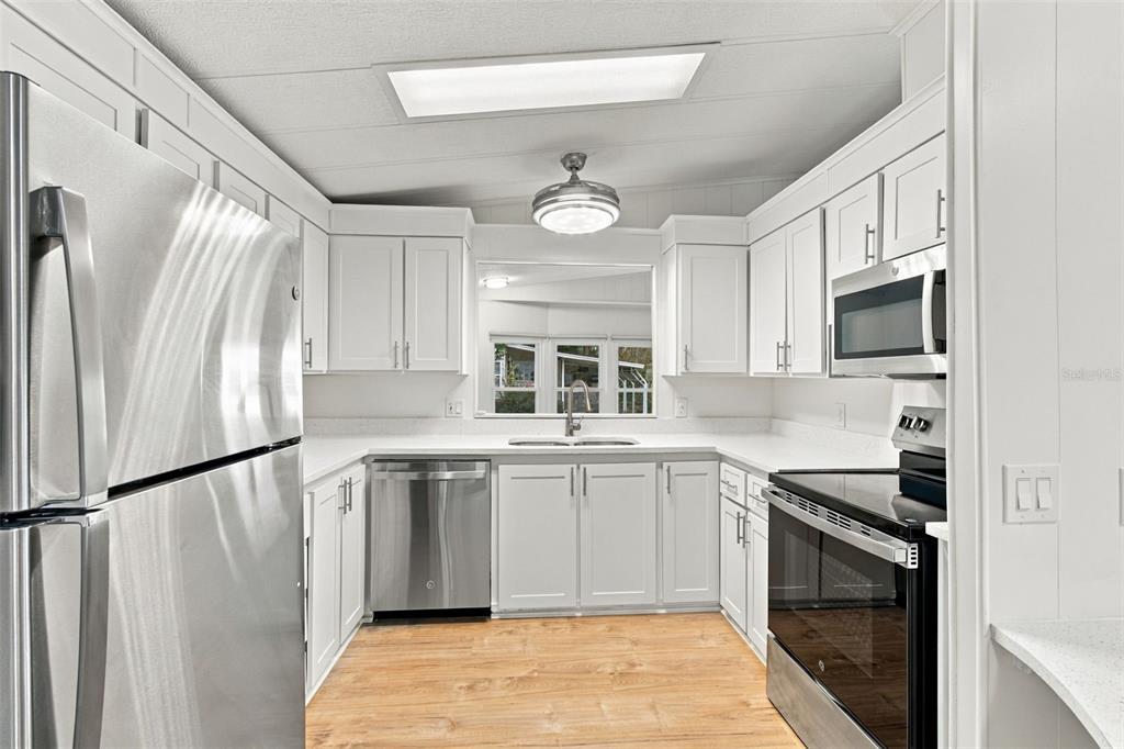 A kitchen with white cabinets, stainless steel appliances, and a white speckled countertop — 130 CLUBVIEW DRIVE UNIT 2, SAFETY HARBOR, FL