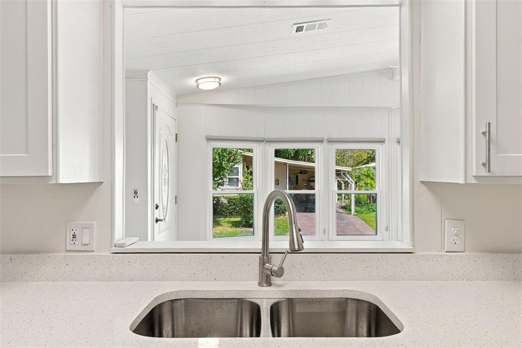 A kitchen features white cabinets, stainless steel appliances, a breakfast bar, and light wood flooring — 130 CLUBVIEW DRIVE UNIT 2, SAFETY HARBOR, FL