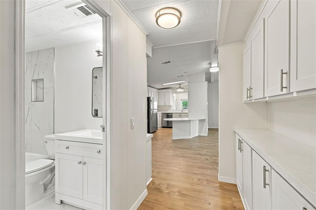 A kitchen features white cabinets, stainless steel appliances, and light wood-look flooring — 130 CLUBVIEW DRIVE UNIT 2, SAFETY HARBOR, FL