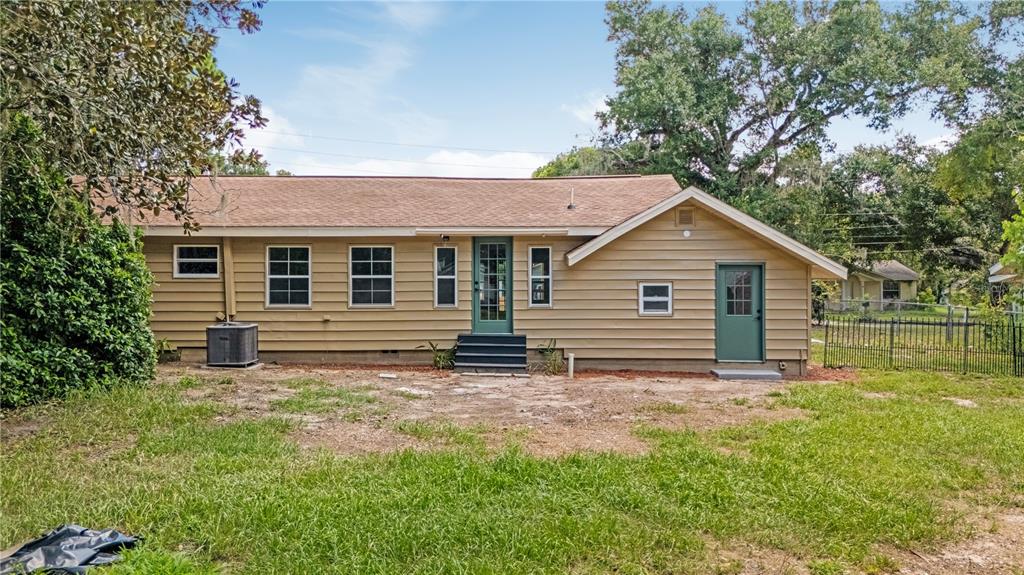 The exterior of a tan, single-story house with a green door and a grassy yard — 305 S ROSSITER STREET, MOUNT DORA, FL