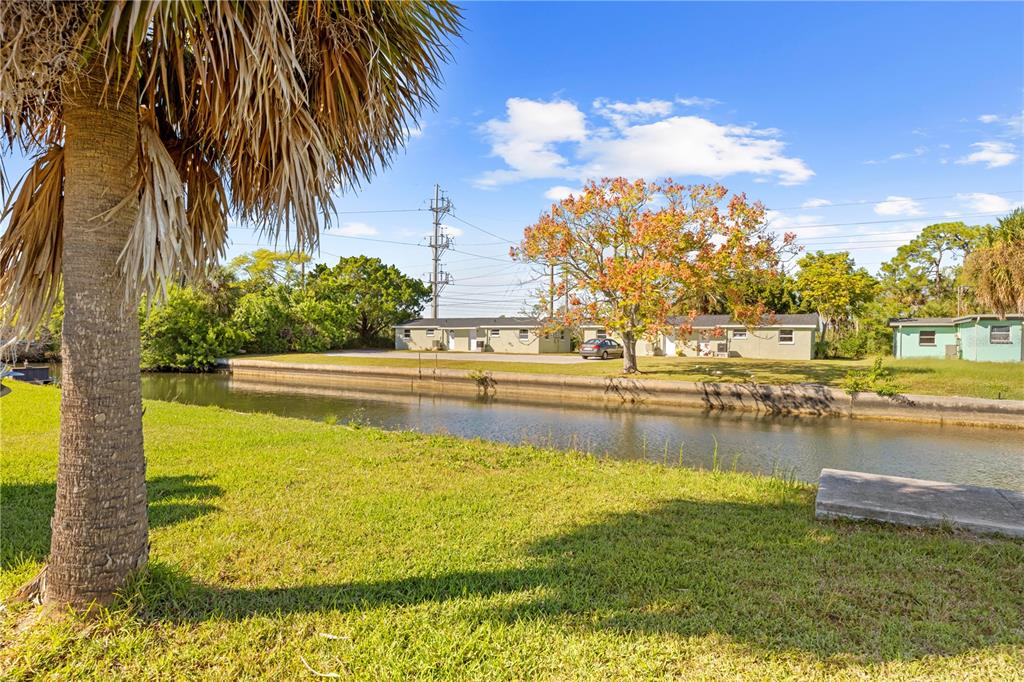 A canal flows in front of a grassy yard with palm trees and residential buildings — 0 SHEEPSHEAD DRIVE, HUDSON, FL