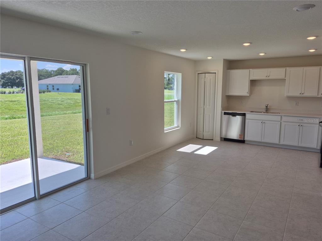 A kitchen with white cabinets, stainless steel appliances, and light tile flooring — 8810 PINE BARK WAY, WILDWOOD, FL