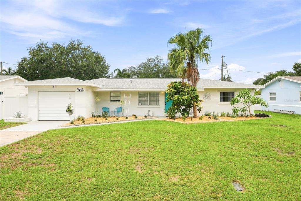 A single-story white brick house with a garage, palm tree, and landscaped front yard — 1842 59TH WAY N, ST PETERSBURG, FL