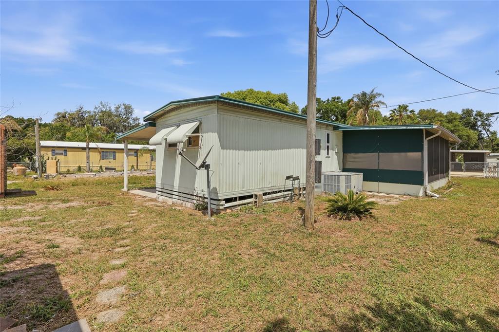 A screened-in porch with a concrete floor, metal siding, and a view of the yard — 37622 MARCH LANE, ZEPHYRHILLS, FL
