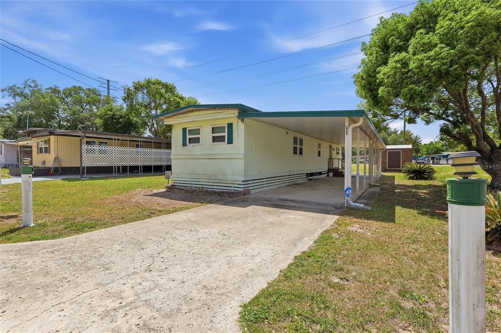 A covered porch features a teal door, gray concrete flooring, and a screened-in seating area — 37622 MARCH LANE, ZEPHYRHILLS, FL