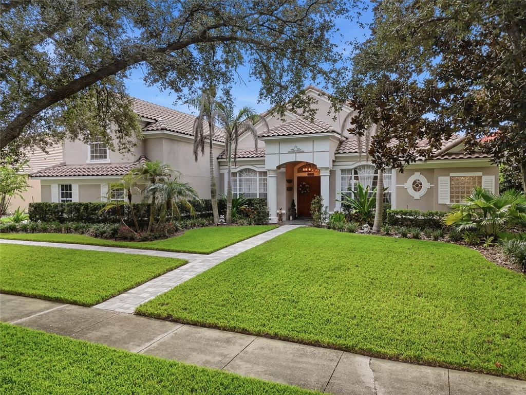 A two-story suburban house with a tiled roof, arched entryway, and a manicured front lawn — 2426 BAESEL VIEW DRIVE, ORLANDO, FL