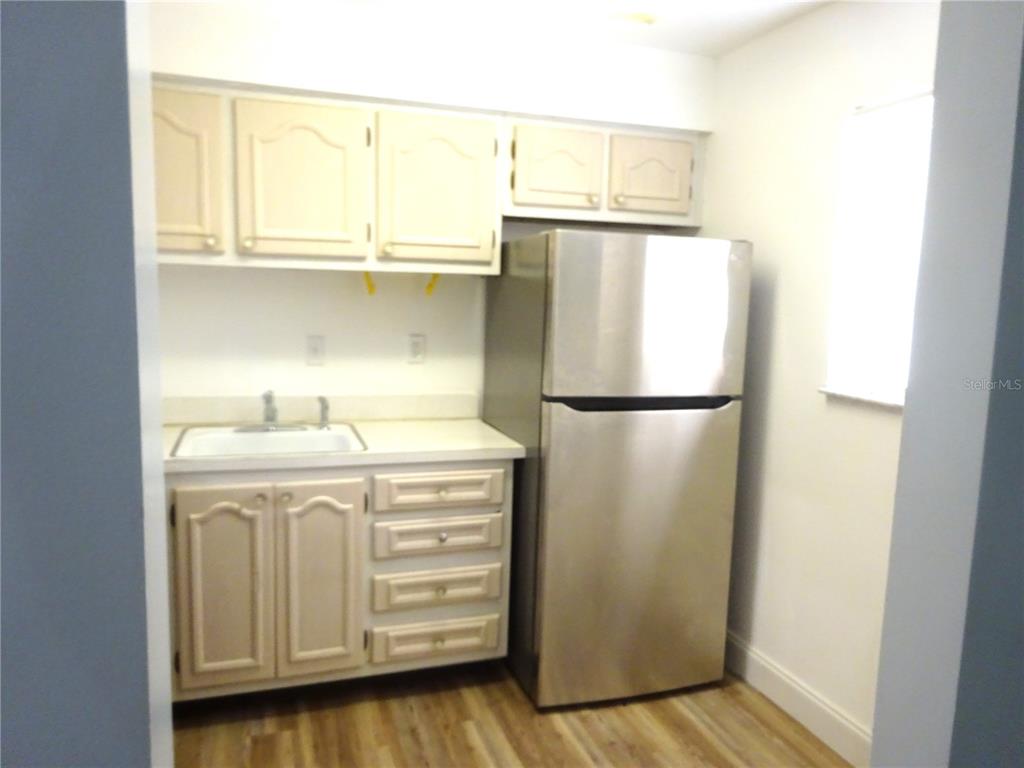 A kitchen features light-colored cabinets, a white countertop with a sink, and a stainless steel refrigerator — 2864 N POWERS DRIVE UNIT 156, ORLANDO, FL
