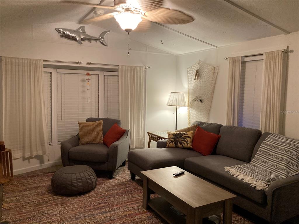 A covered outdoor seating area with a wind chime sits beside a tan storage shed — 3723 116TH STREET W, BRADENTON, FL