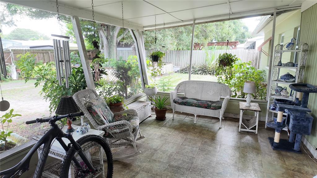 A screened-in porch features wicker furniture, a bicycle, and a view of the backyard — 7485 17TH STREET N, ST PETERSBURG, FL