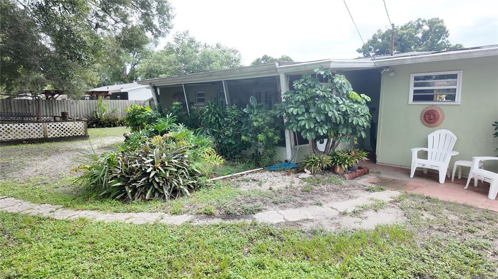 A light green house exterior features a screened porch, landscaping, and two white chairs — 7485 17TH STREET N, ST PETERSBURG, FL