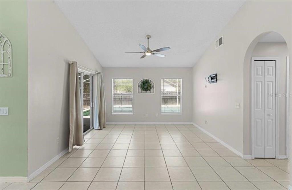 A kitchen with white cabinets, stainless steel appliances, and tile flooring under a vaulted ceiling — 40045 PALM STREET, LADY LAKE, FL