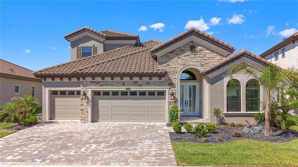 A single-family home with a stone facade, tile roof, and a three-car garage — 11008 RUSTIC TIMBER LOOP, SAN ANTONIO, FL