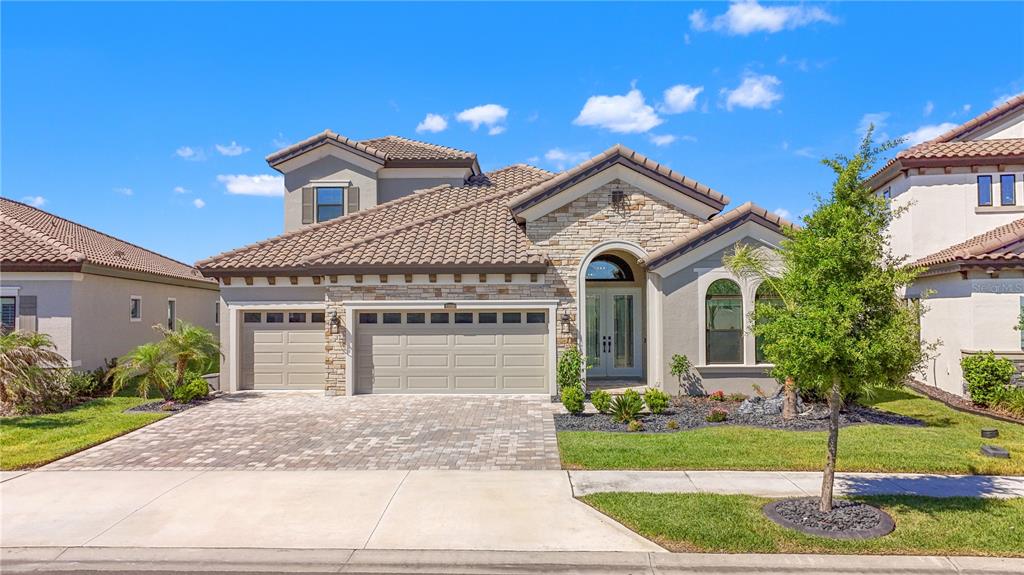 A two-story suburban house with a stone facade, tile roof, and a three-car garage — 11008 RUSTIC TIMBER LOOP, SAN ANTONIO, FL