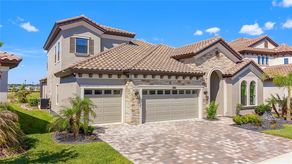 A two-story suburban house with a stone facade, tile roof, and a paved driveway — 11008 RUSTIC TIMBER LOOP, SAN ANTONIO, FL