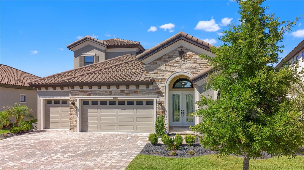 A two-story house with a stone facade, tile roof, and a three-car garage — 11008 RUSTIC TIMBER LOOP, SAN ANTONIO, FL