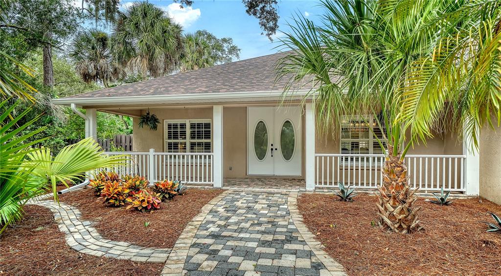 A single-story house features a stone walkway leading to a white double-door entrance and porch — 2166 SYLVAN LEA DRIVE, SARASOTA, FL