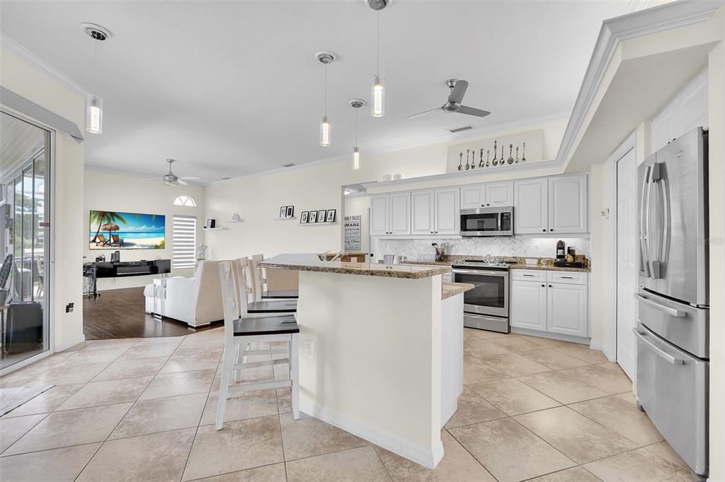 An open-concept kitchen with white cabinets, stainless steel appliances, and a breakfast bar — 6817 CORRAL CIRCLE, SARASOTA, FL