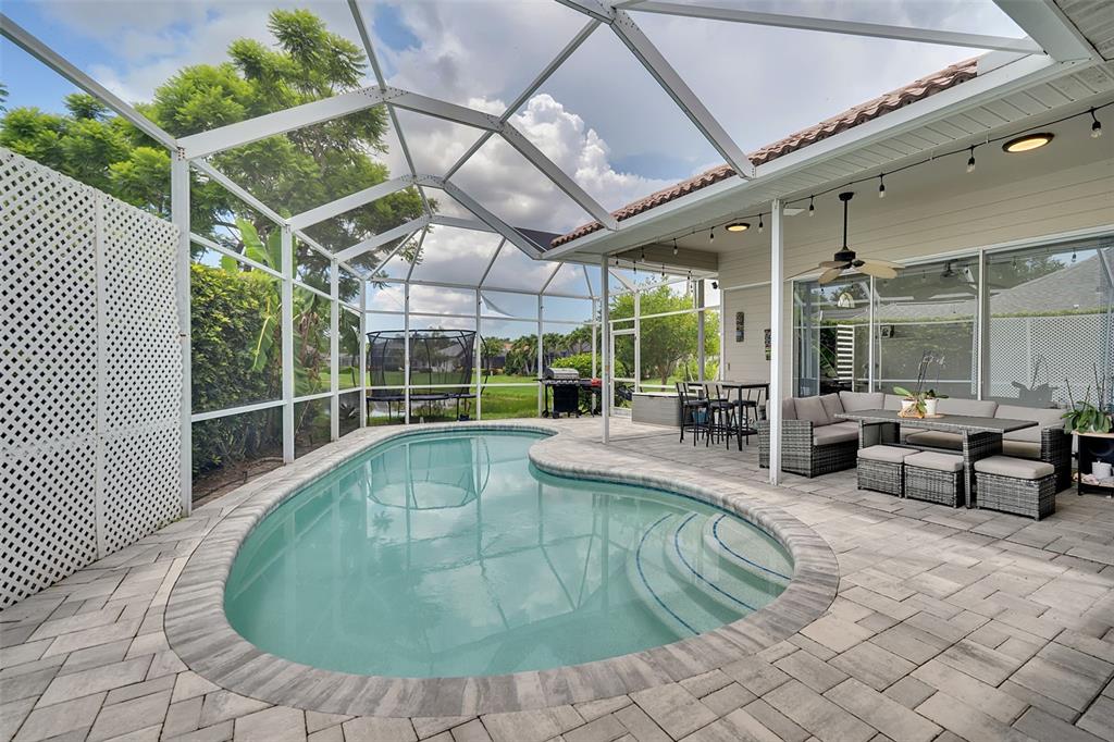 A screened-in patio features a kidney-shaped pool, outdoor seating, and a grill area — 6817 CORRAL CIRCLE, SARASOTA, FL