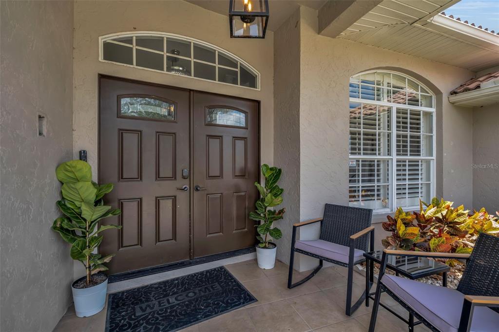 A covered entryway features double brown doors, a welcome mat, and two chairs — 6817 CORRAL CIRCLE, SARASOTA, FL