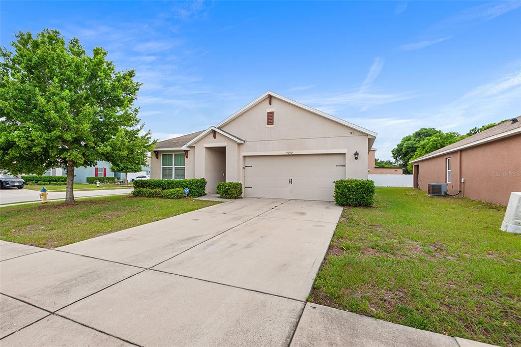 A single-story suburban house with a beige stucco exterior, a two-car garage, and a lawn — 4140 SOPHIA BOULEVARD, WINTER HAVEN, FL