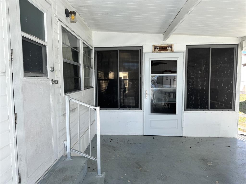 A covered porch features a white door, sliding windows, and a metal railing — 254 SOUTHWINDS DRIVE, SARASOTA, FL