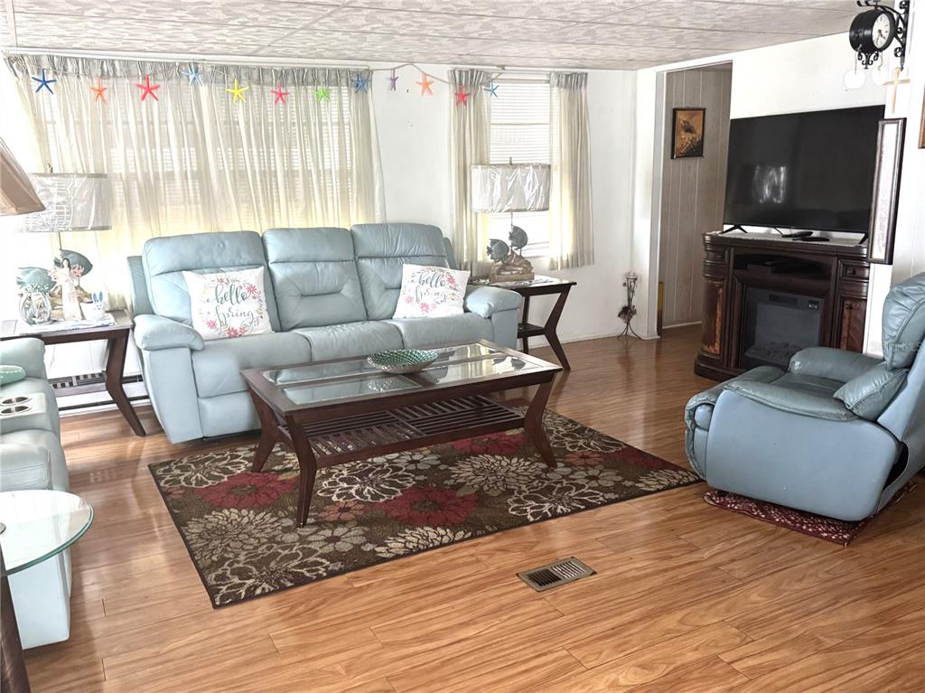 A living room features light blue leather furniture, a floral area rug, and wood flooring — 254 SOUTHWINDS DRIVE, SARASOTA, FL
