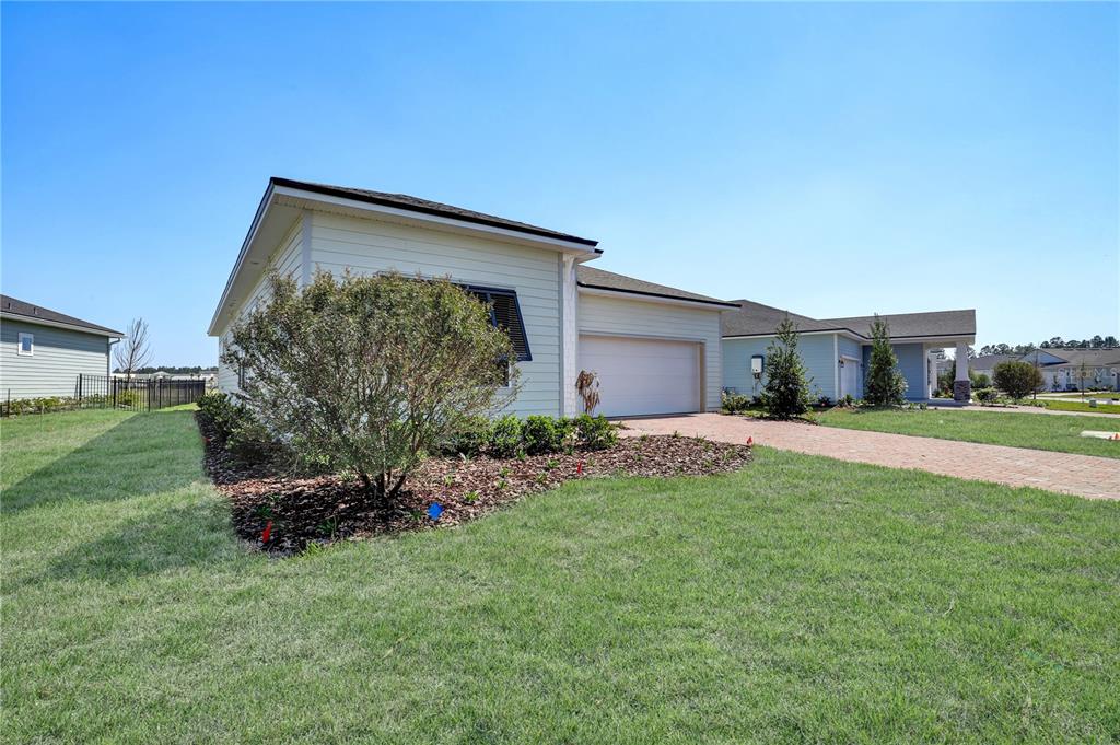 A light-colored single-story house with a brick driveway and a landscaped front yard — 230 APPLEJACK DRIVE, ST AUGUSTINE, FL