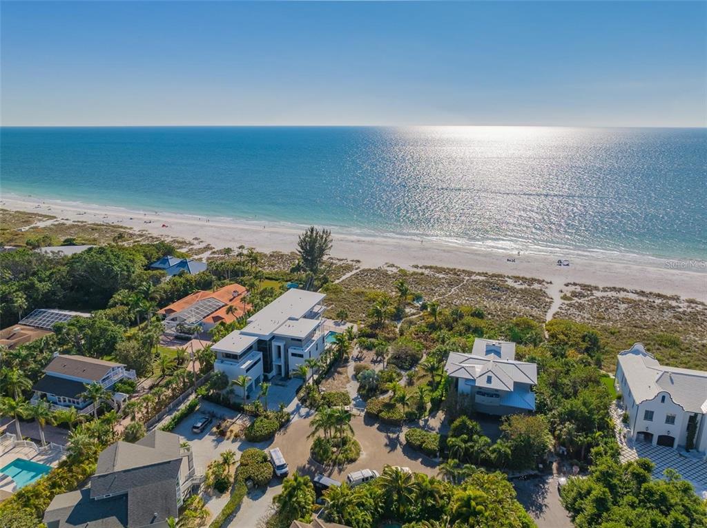 An aerial view of several coastal homes situated along a sandy beach and the ocean — 102 SUNSET LANE, HOLMES BEACH, FL