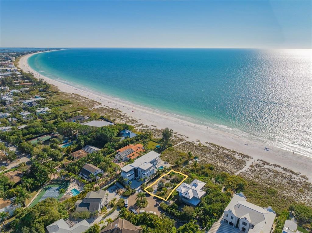 An aerial view shows a vacant, rectangular lot outlined in yellow near a sandy beach — 102 SUNSET LANE, HOLMES BEACH, FL
