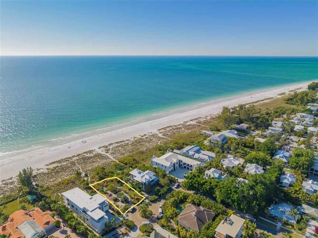 An aerial view shows a vacant, rectangular lot outlined in yellow near a sandy beach — 102 SUNSET LANE, HOLMES BEACH, FL