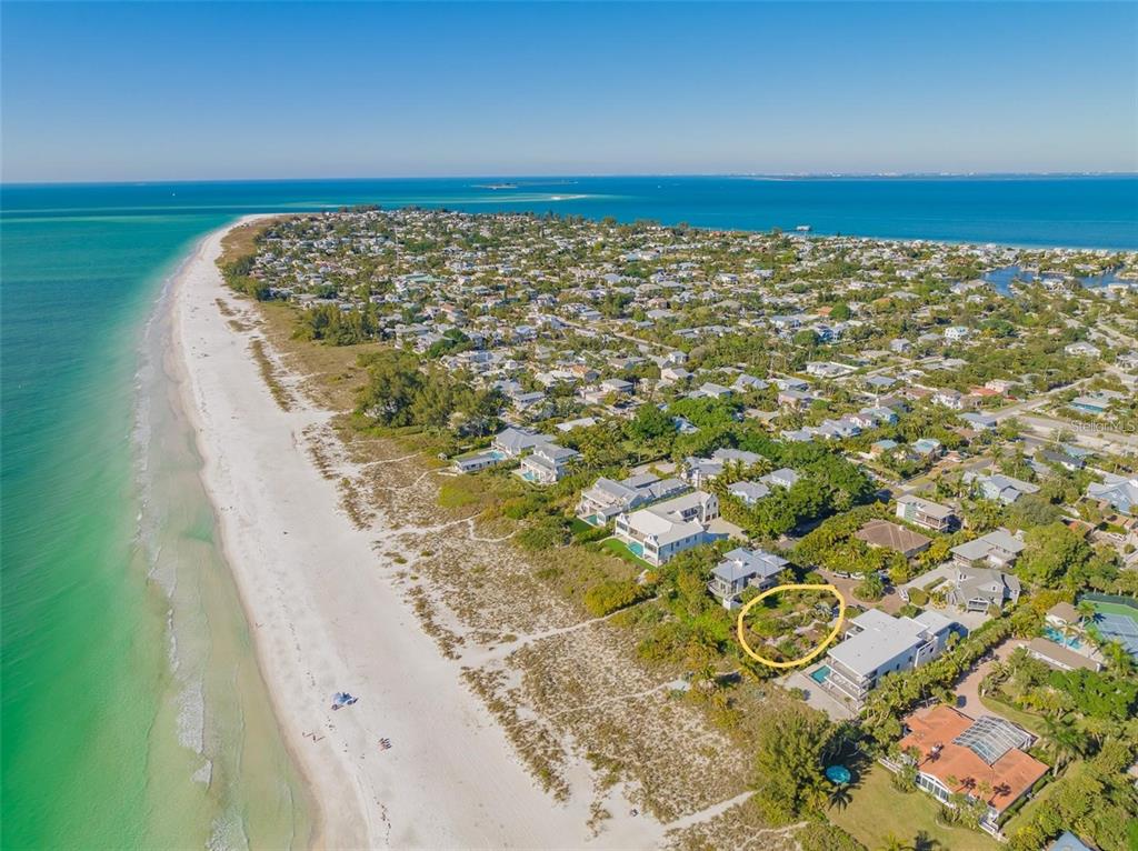 An aerial view shows a coastal neighborhood with a vacant lot circled in yellow — 102 SUNSET LANE, HOLMES BEACH, FL