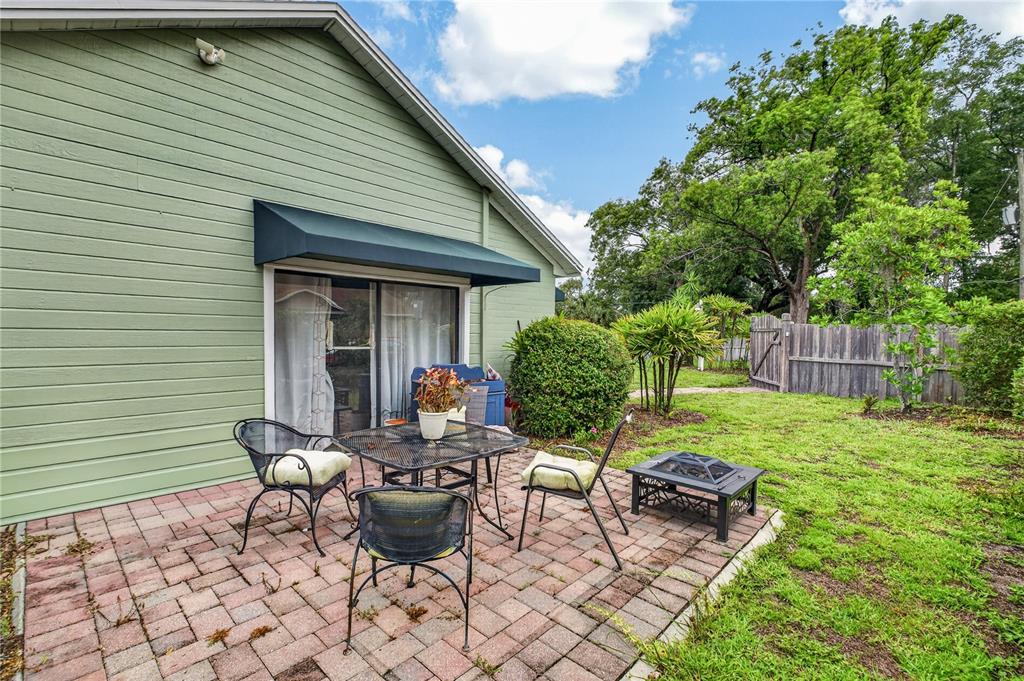 A patio with a metal table and chairs sits outside a house with green siding — 1802 CHAMBERLIN STREET UNIT 2, ORLANDO, FL